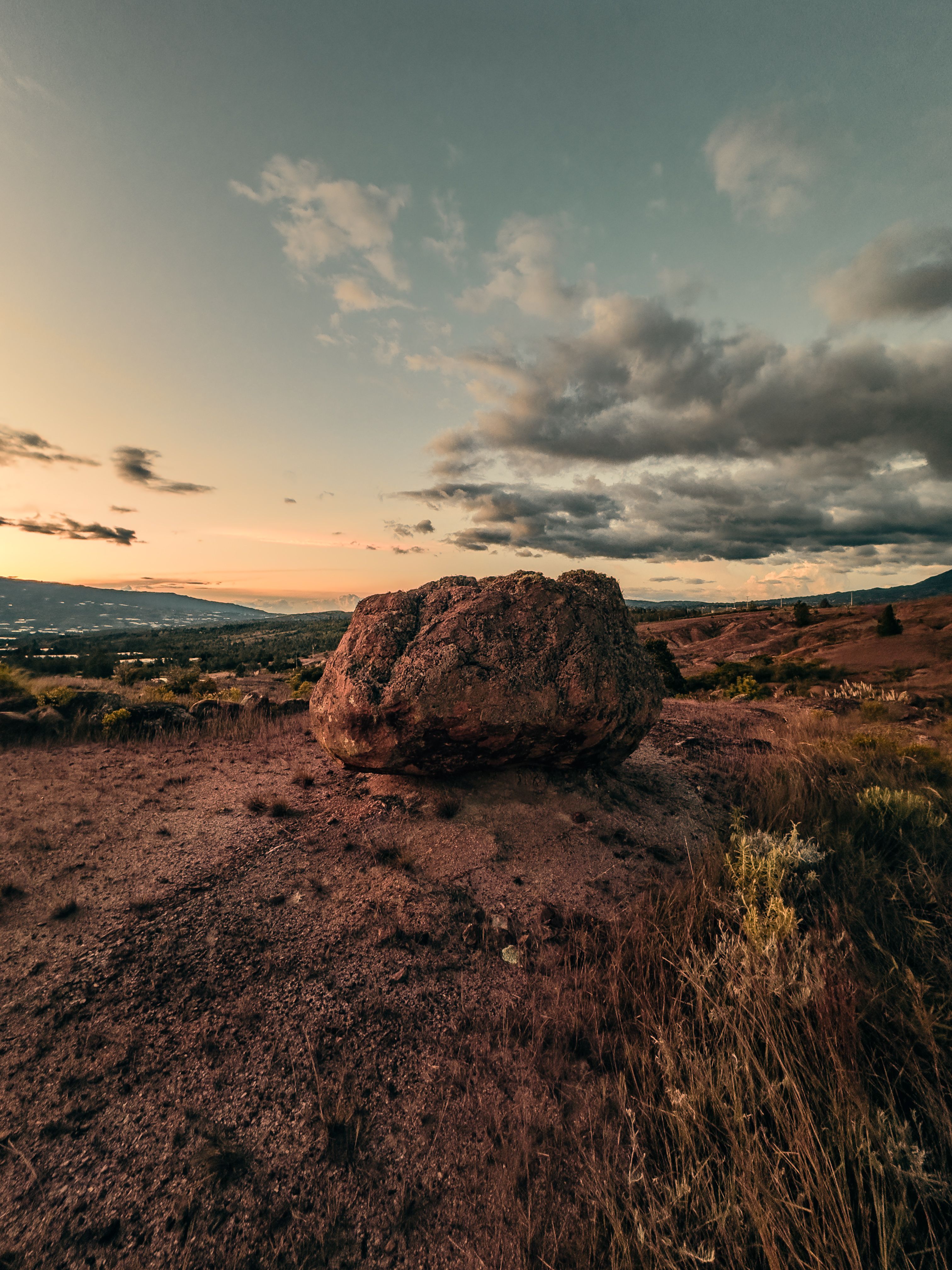 Fotomural Una vista impresionante de una gran roca en una colina al atardecer con un cielo dramático en Tunja, Colombia.
