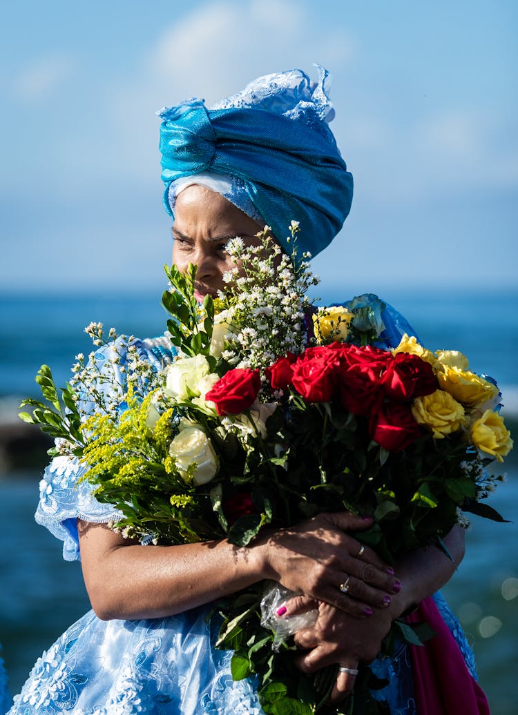 Woman In Blue Head Wrap Holding Bouquet Of Flowers