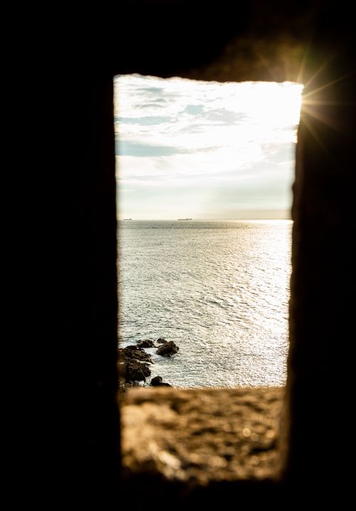Free Captivating view of the ocean through a stone windowframe at sunset in Bahia, Brazil. Stock Photo