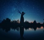 星空下，一名女子的剪影站在湖边，映照出宁静