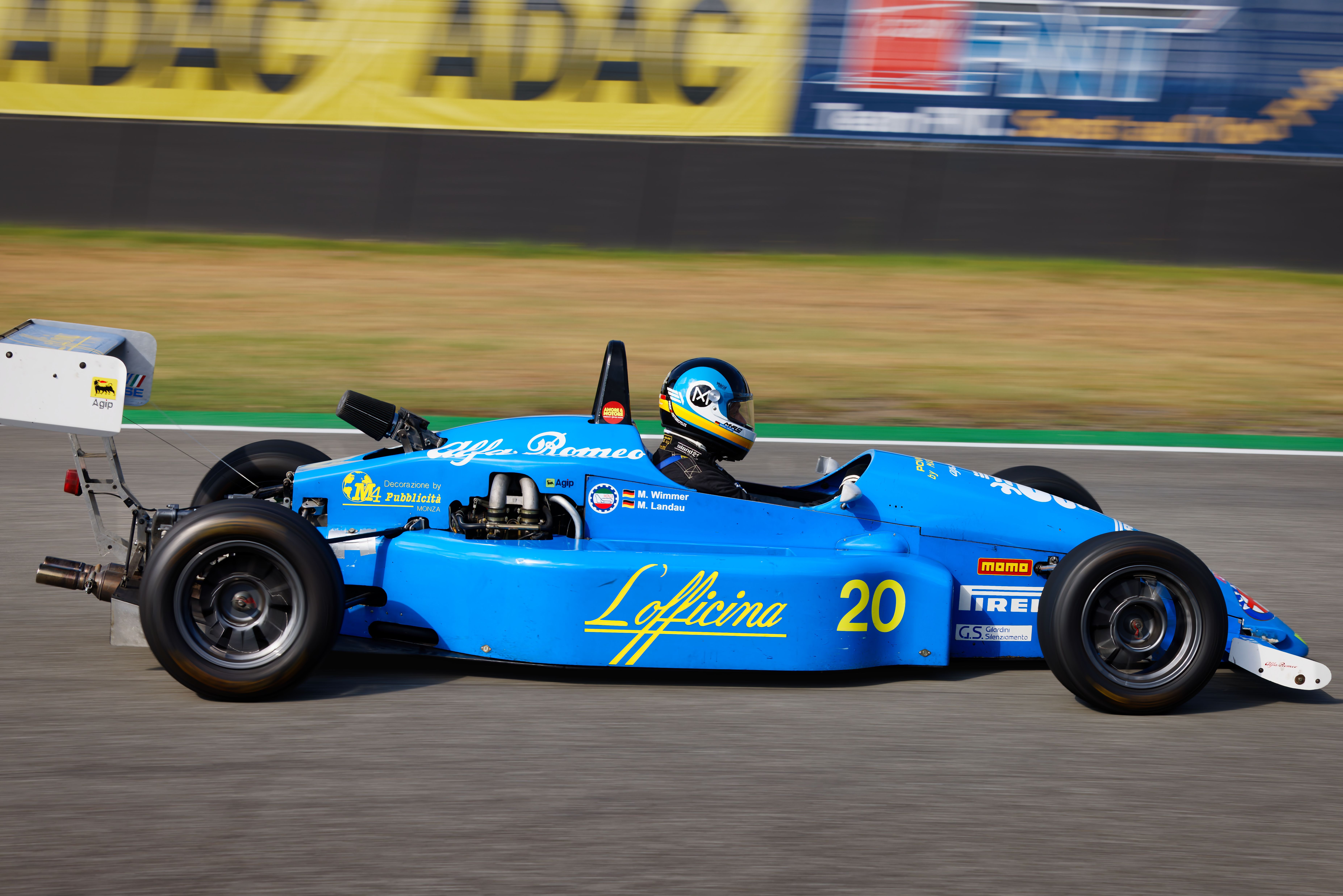 Blue race car speeding down the track during a daytime race event.