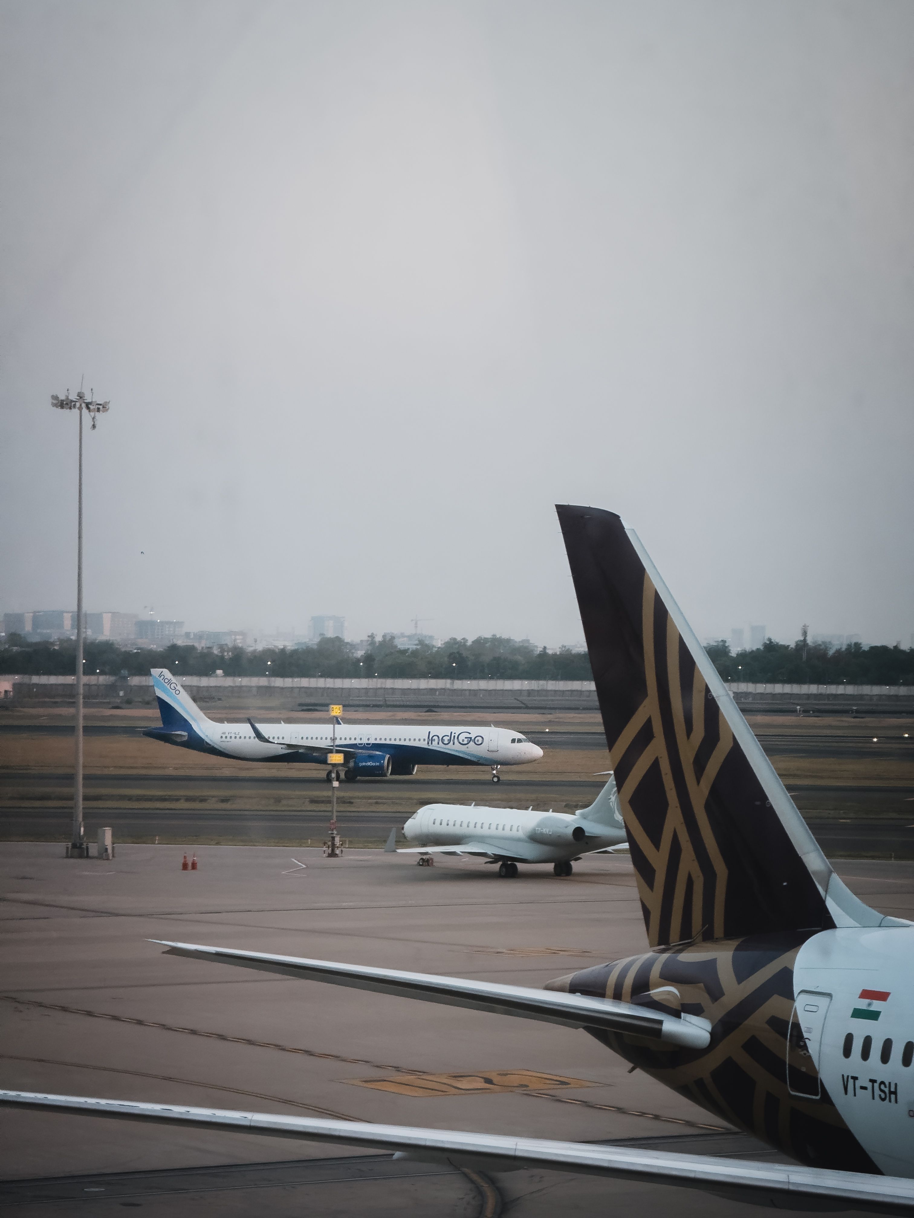 Multiple airplanes on the tarmac and taxiing at Indira Gandhi Airport in New Delhi, India.