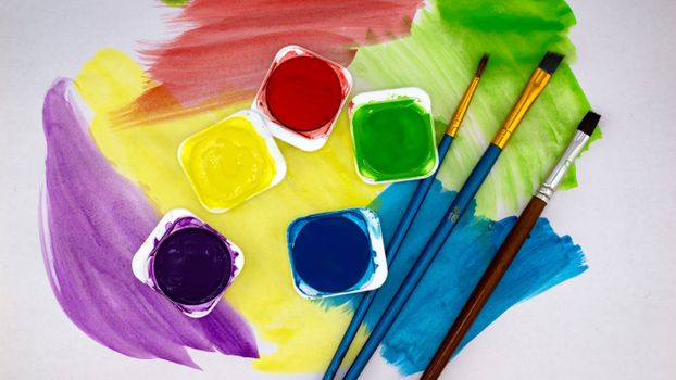Vibrant watercolor paints and brushes on a white canvas. Perfect for creative art projects.