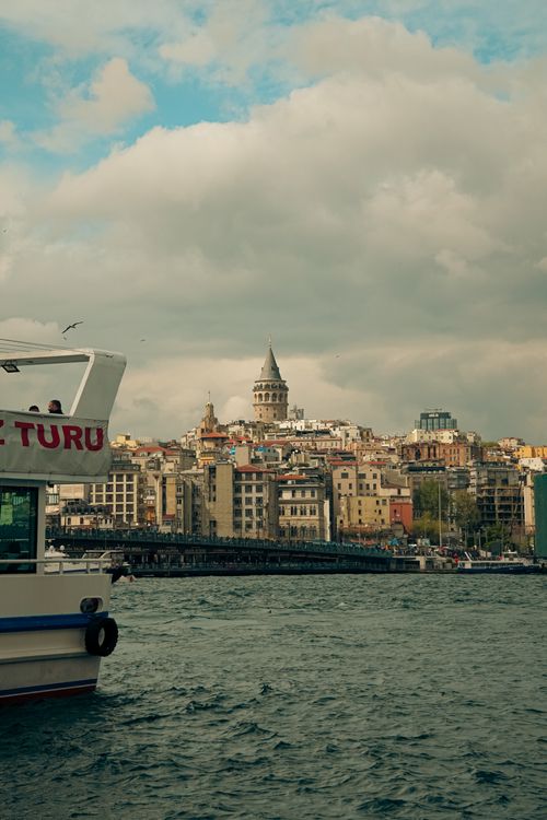 Free Breathtaking scene of Galata Tower, Istanbul, with boat on the Bosphorus under a partly cloudy sky. Stock Photo