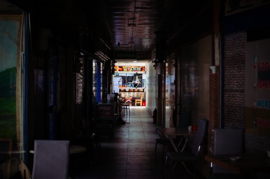 Moody indoor alley in Ankara leading to a colorful and inviting cafe entrance.