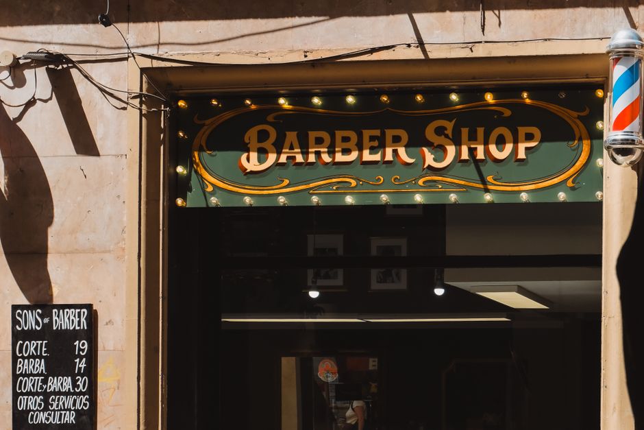 Uma entrada de barbearia em estilo vintage em Barcelona, com letreiros e decoração clássicos.