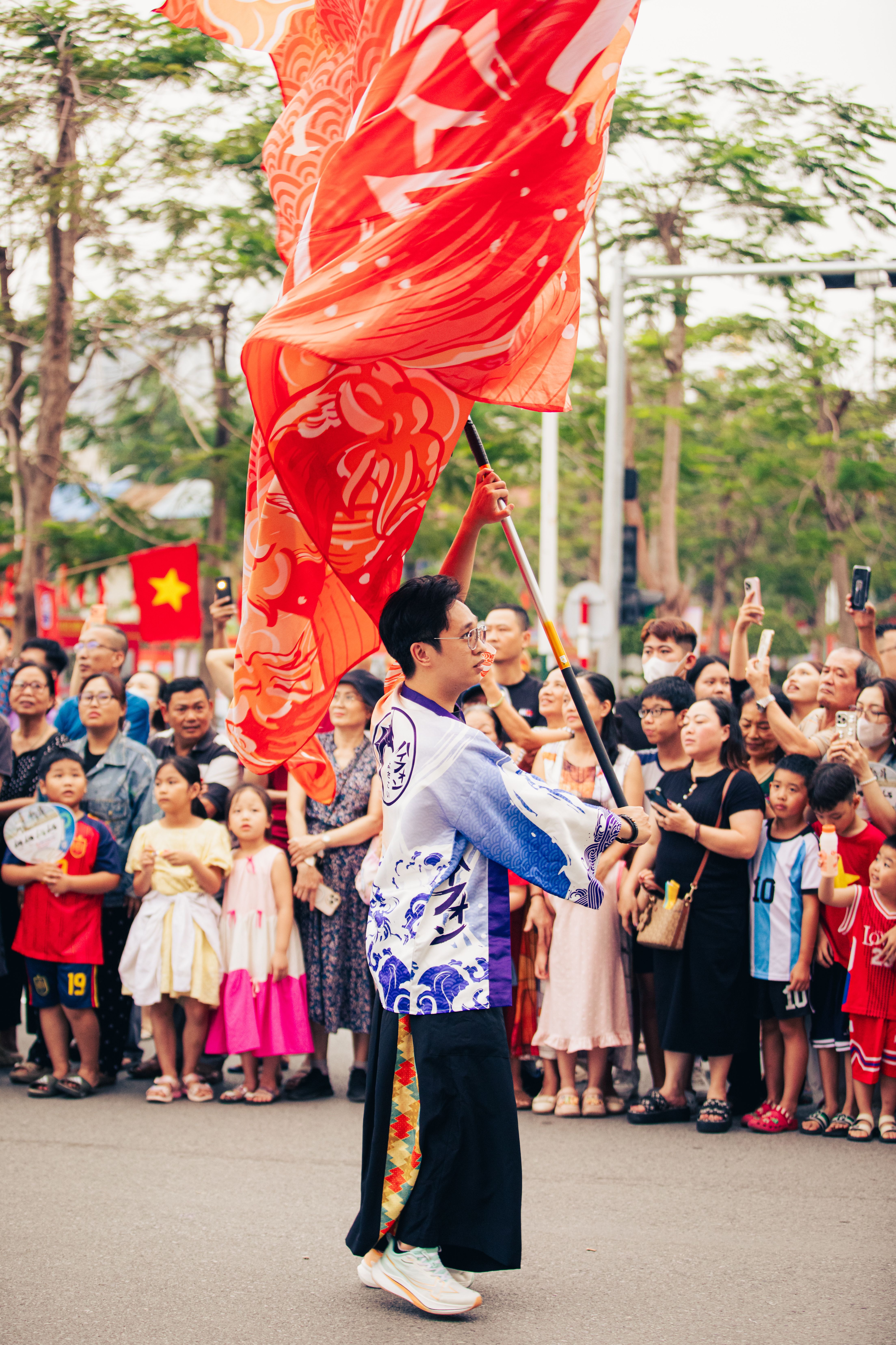 A vibrant street parade in Haiphong, Vietnam showcasing cultural performance with flags.