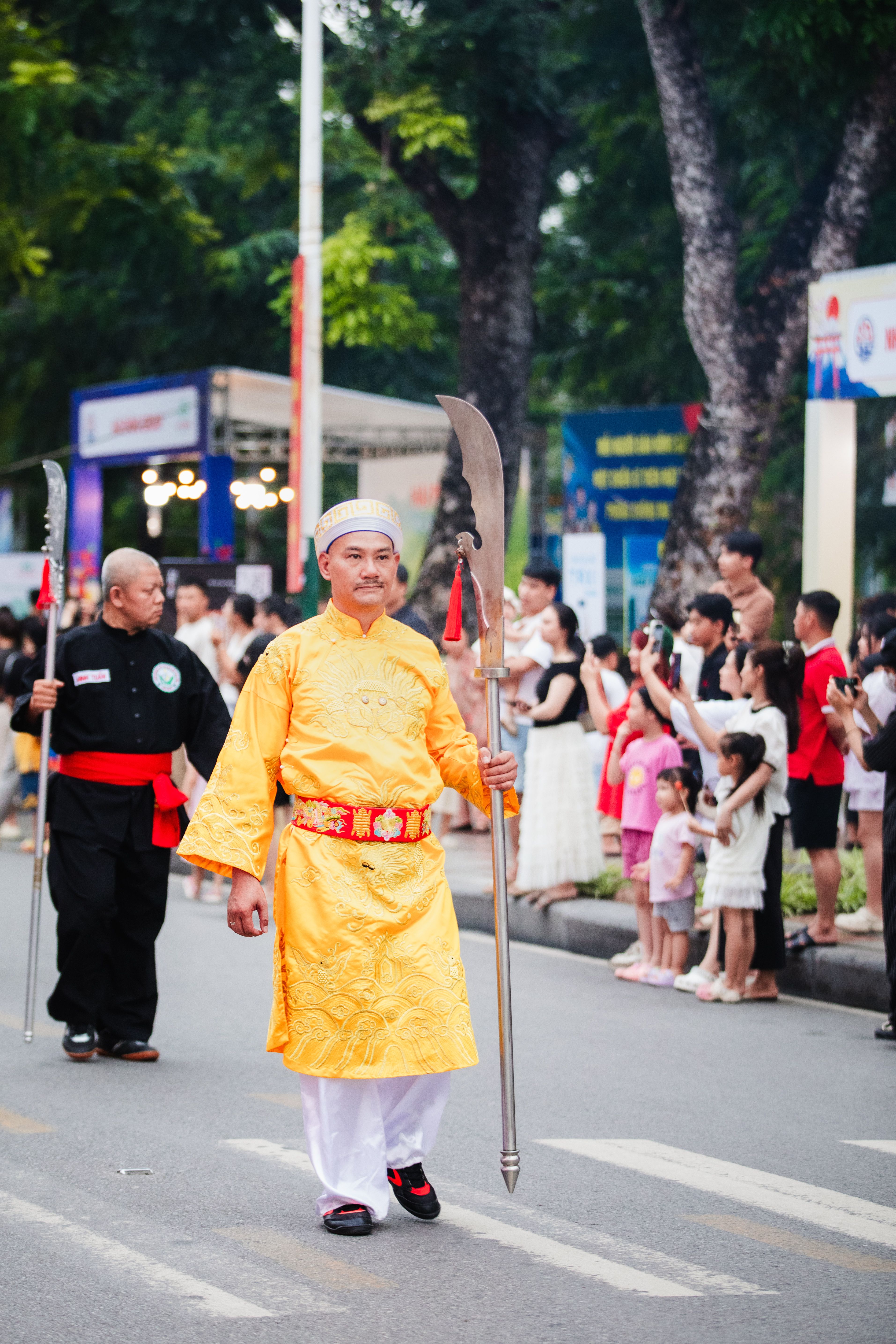 Colorful traditional parade featuring participants in vibrant costumes on a street in Haiphong, Vietnam.