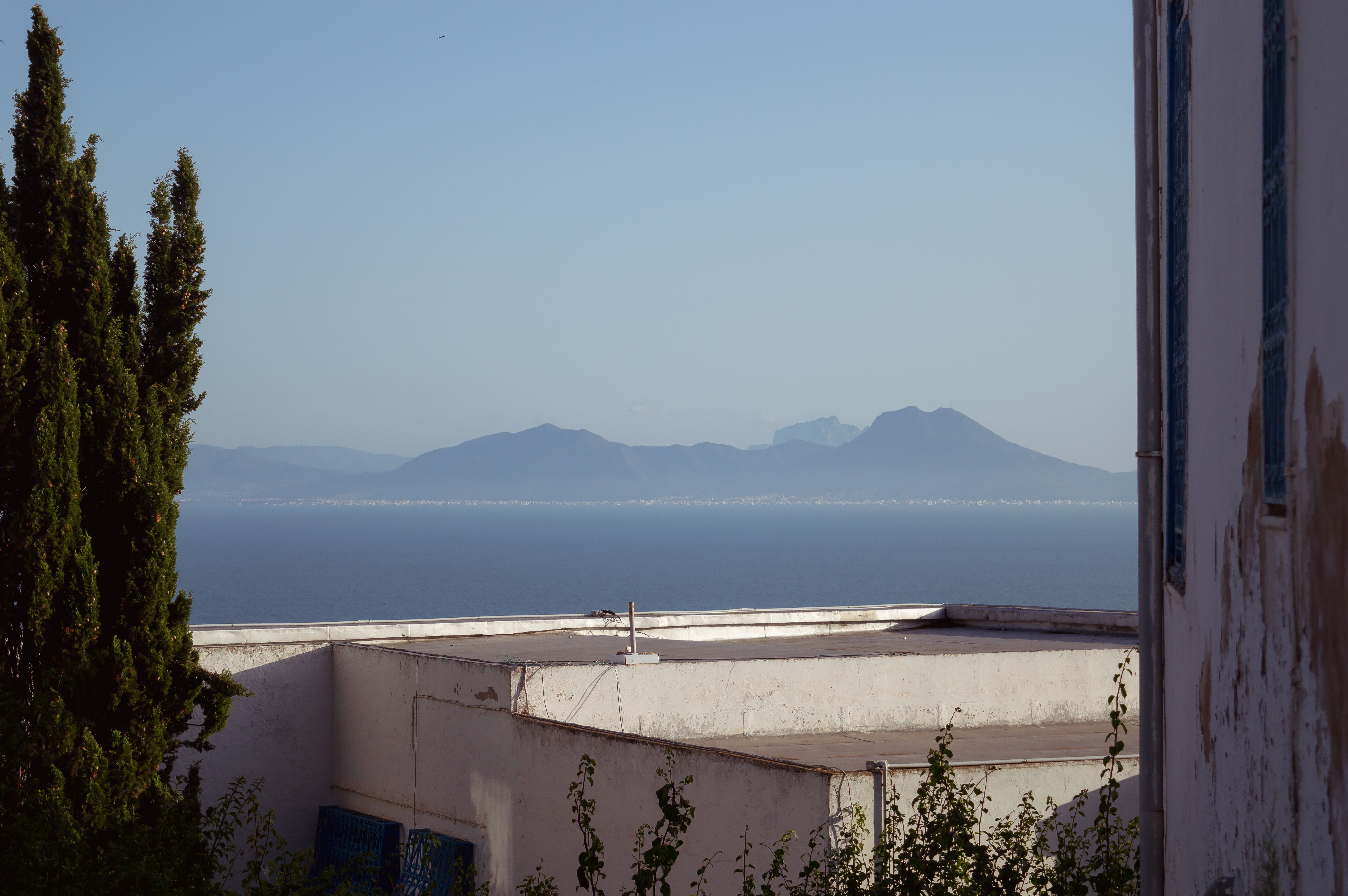 Peaceful seaside view with distant mountains under clear blue sky, perfect for travel and nature enthusiasts.