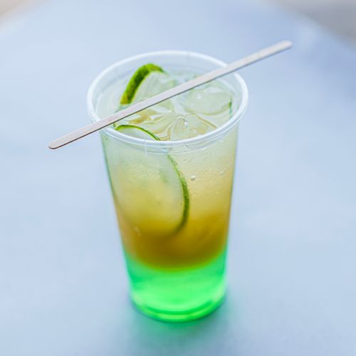 Free Close-up of a refreshing lime iced drink in a plastic cup with a wooden stirrer. Stock Photo