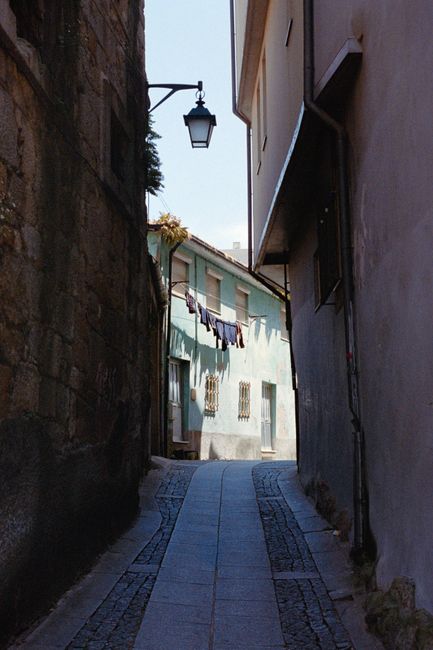 A picturesque narrow alley with colorful facade and laundry hanging under a streetlamp in an old European town.
