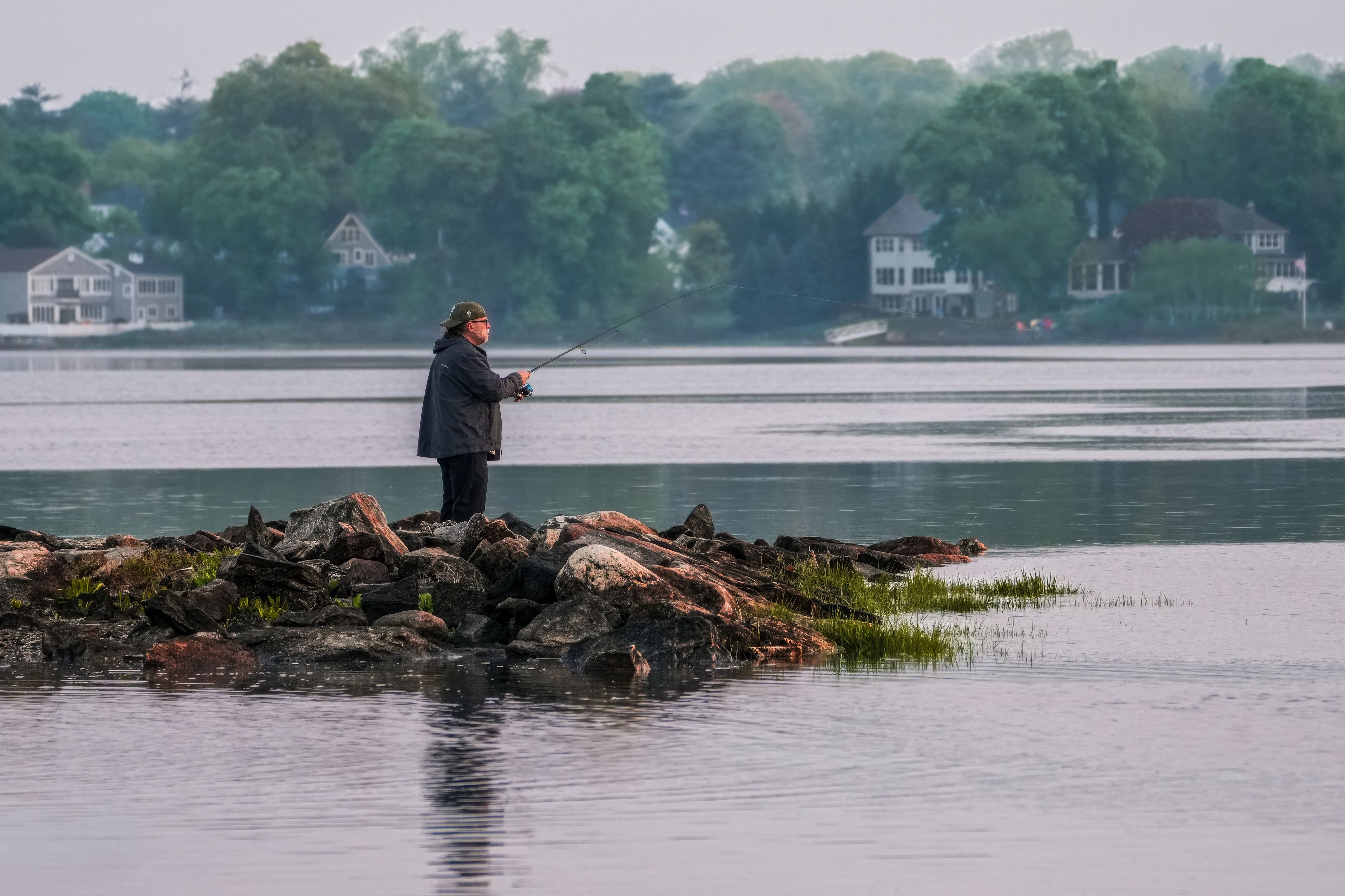 夜の堤防でアジングをするアングラーの後ろ姿