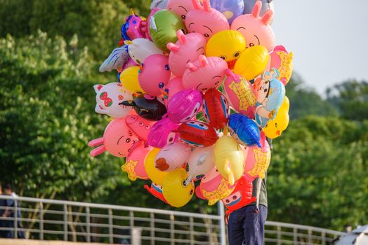 Vibrant cartoon character balloons being sold outdoors on a sunny day in a park.