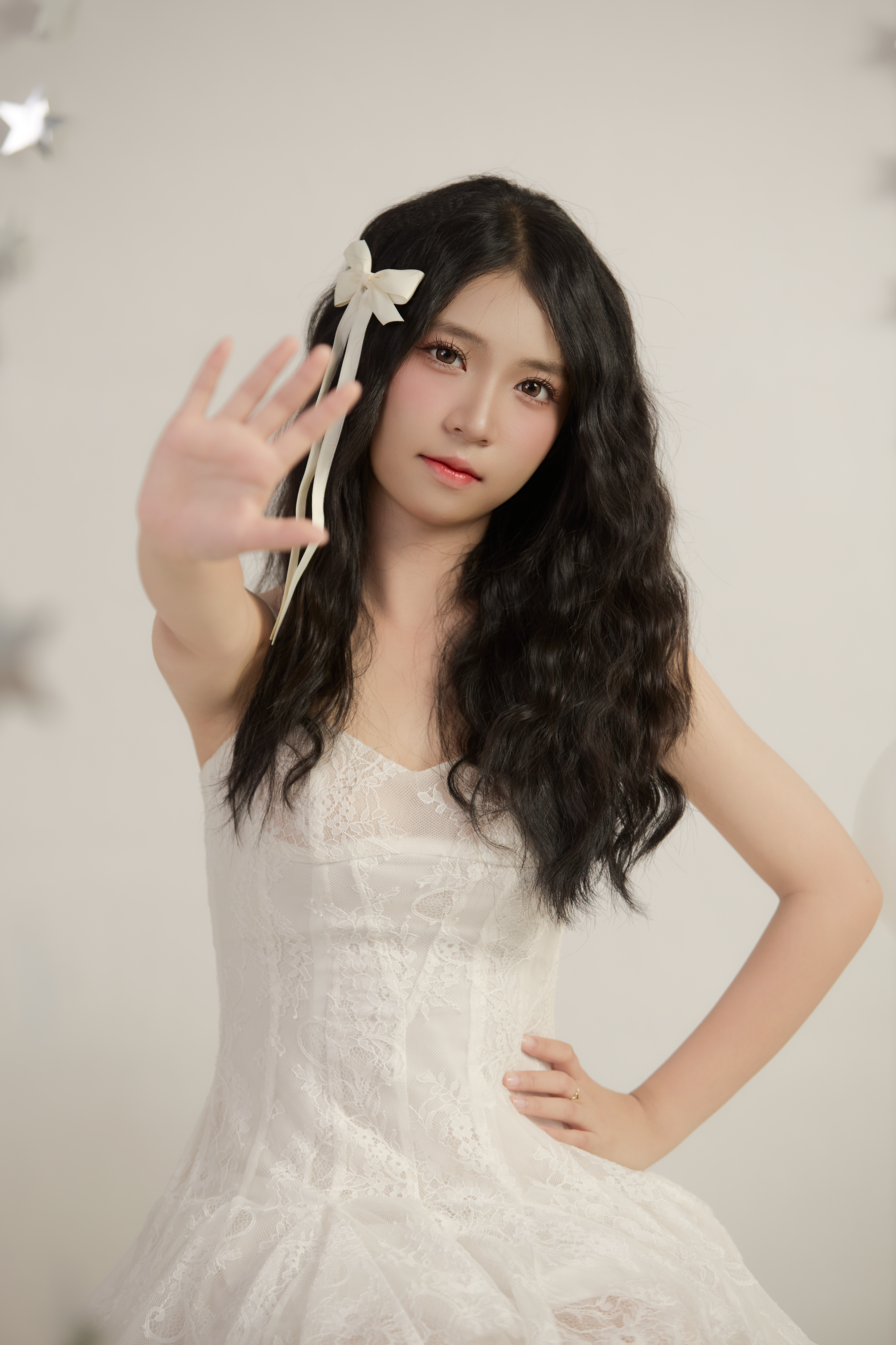 Young woman in a white dress making a stop gesture with her hand.