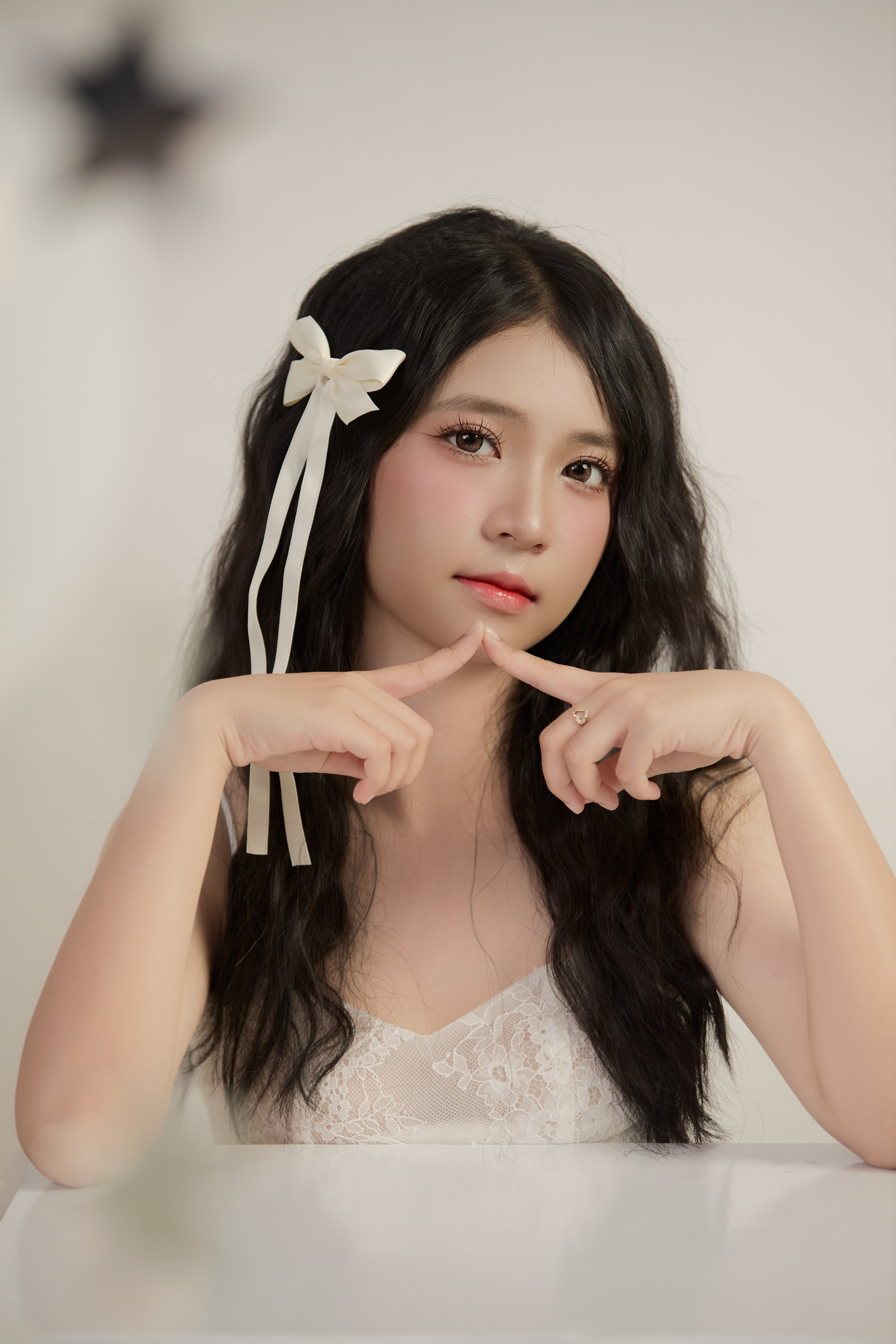 Elegant portrait of a woman with a white bow in her hair, posing indoors.