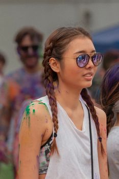 A young woman enjoying a vibrant, paint-splattered festival outdoors.