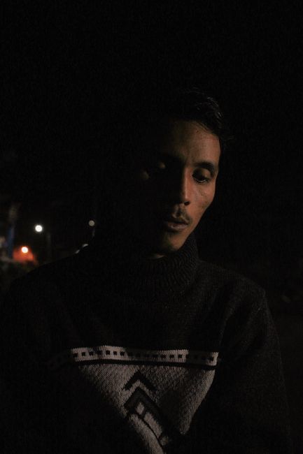 A contemplative portrait of a man in a dark setting, showcasing deep shadows and a reflective mood.