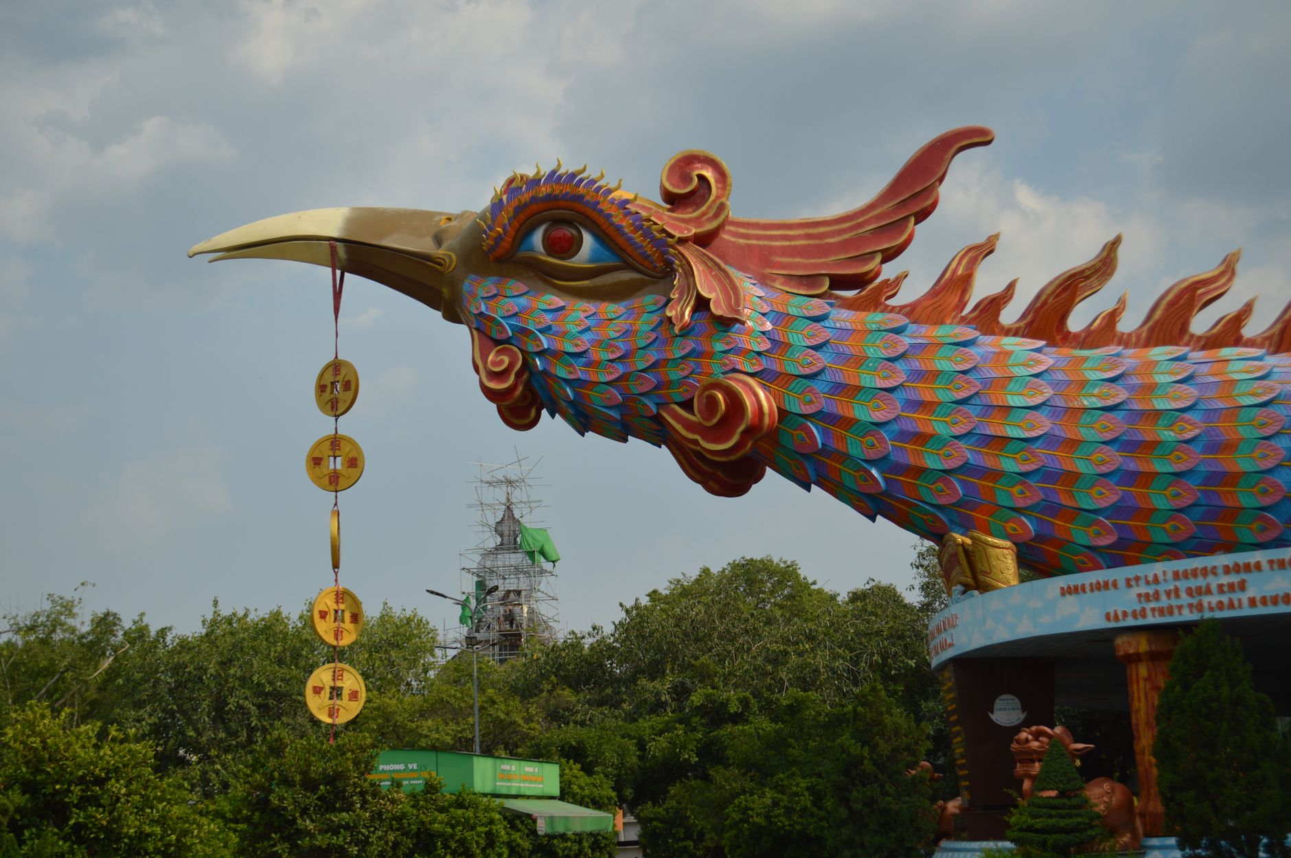 A vibrant phoenix sculpture at Thien Hau Temple with intricate designs and hanging coins.