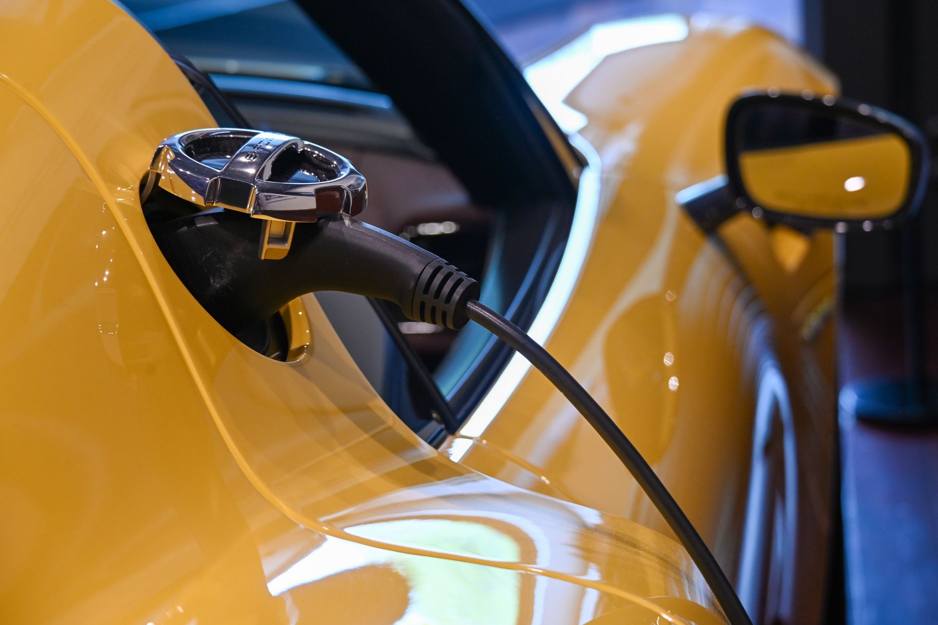 Close-up of a yellow electric vehicle charging with a plugged-in cable indoors.