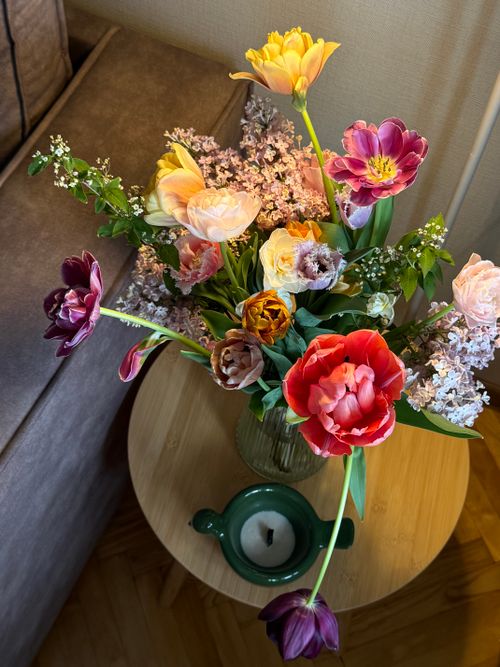 Free Colorful spring bouquet in a vase on a wooden table with candle. Stock Photo