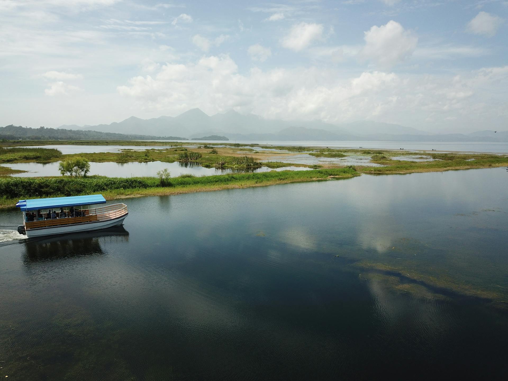 Tranquil boat sailing on a reflective lake surrounded by lush landscape in Honduras.