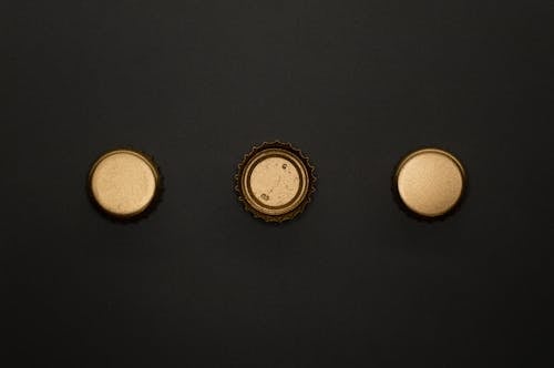 Gold Round Bottle Tops on Black Surface