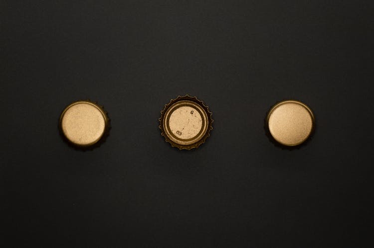 Gold Round Bottle Tops On Black Surface