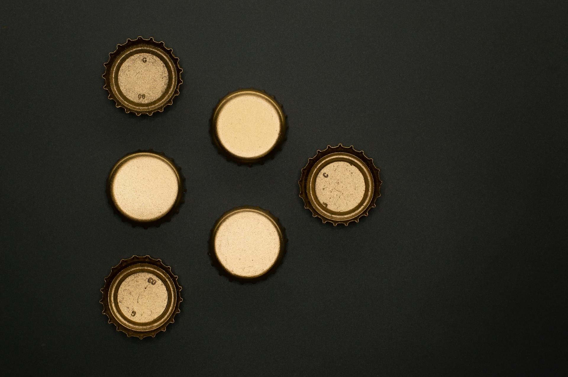 Artistic arrangement of bottle caps on a black background, highlighting recycling concepts.