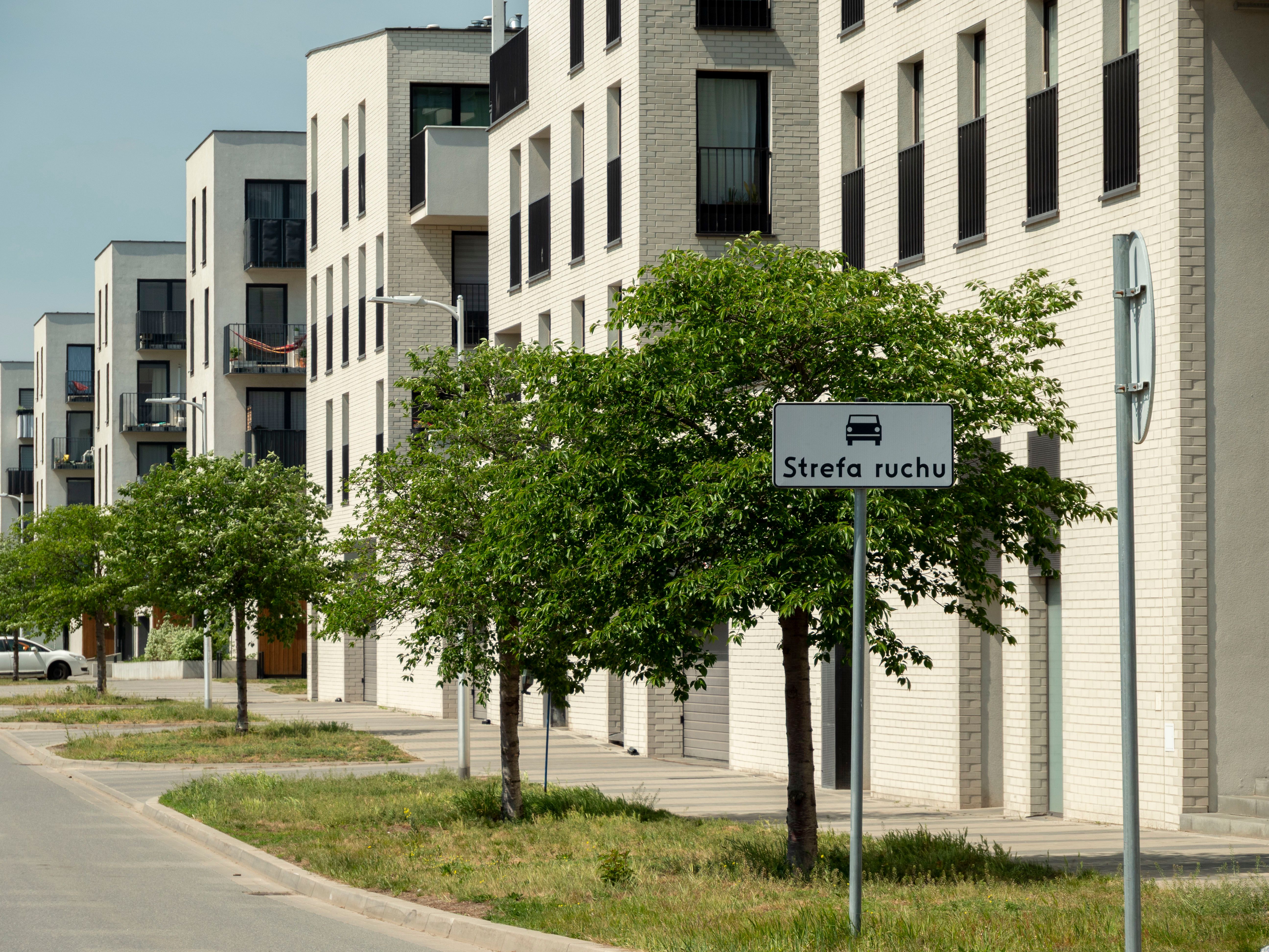 Contemporary apartment buildings with green trees on a sunny street in Wrocław, Poland.