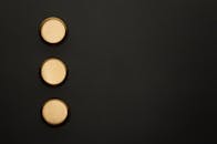 黑色背景上垂直排列着三个金色瓶盖，留有充足的复制空间