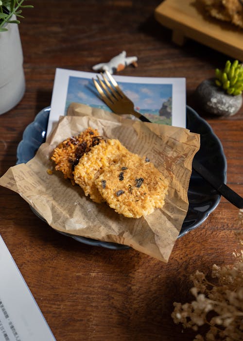 From above of wooden table with tasty baked cookies placed on piece of newspaper on plate