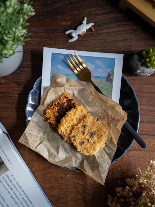 Free Top view composition of delicious biscuits served with fork on plate placed near plants and book on wooden table Stock Photo