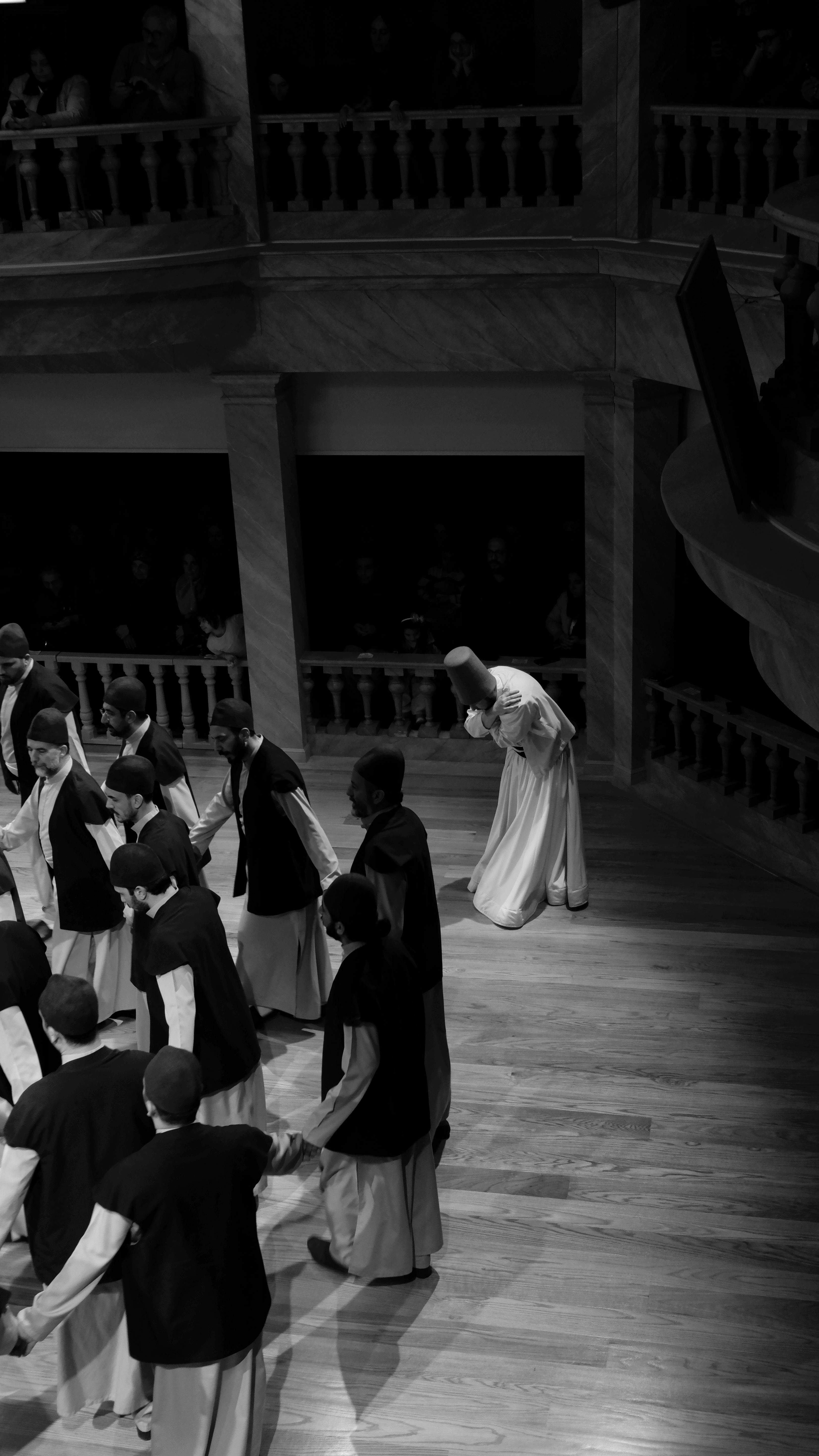 Black and white image of traditional dancers in a historic theater setting.
