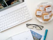 现代工作空间以平板布局的形式，呈现了键盘、眼镜、饼干和记事本