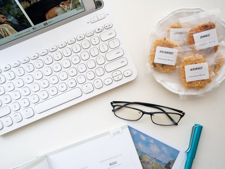 Laptop And Snacks Near Eyeglasses On White Surface