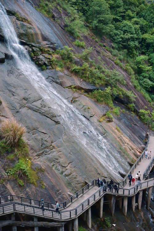 Free A stunning waterfall cascading down rocks with people on a scenic elevated walkway. Stock Photo