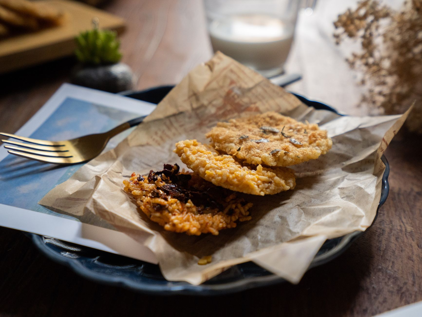 From above of yummy homemade cookies near fork served on ceramic plate with papers placed against glass of milk on wooden table