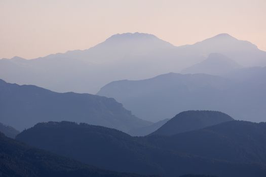 Serene view of mountains with layers fading into the mist during sunset.