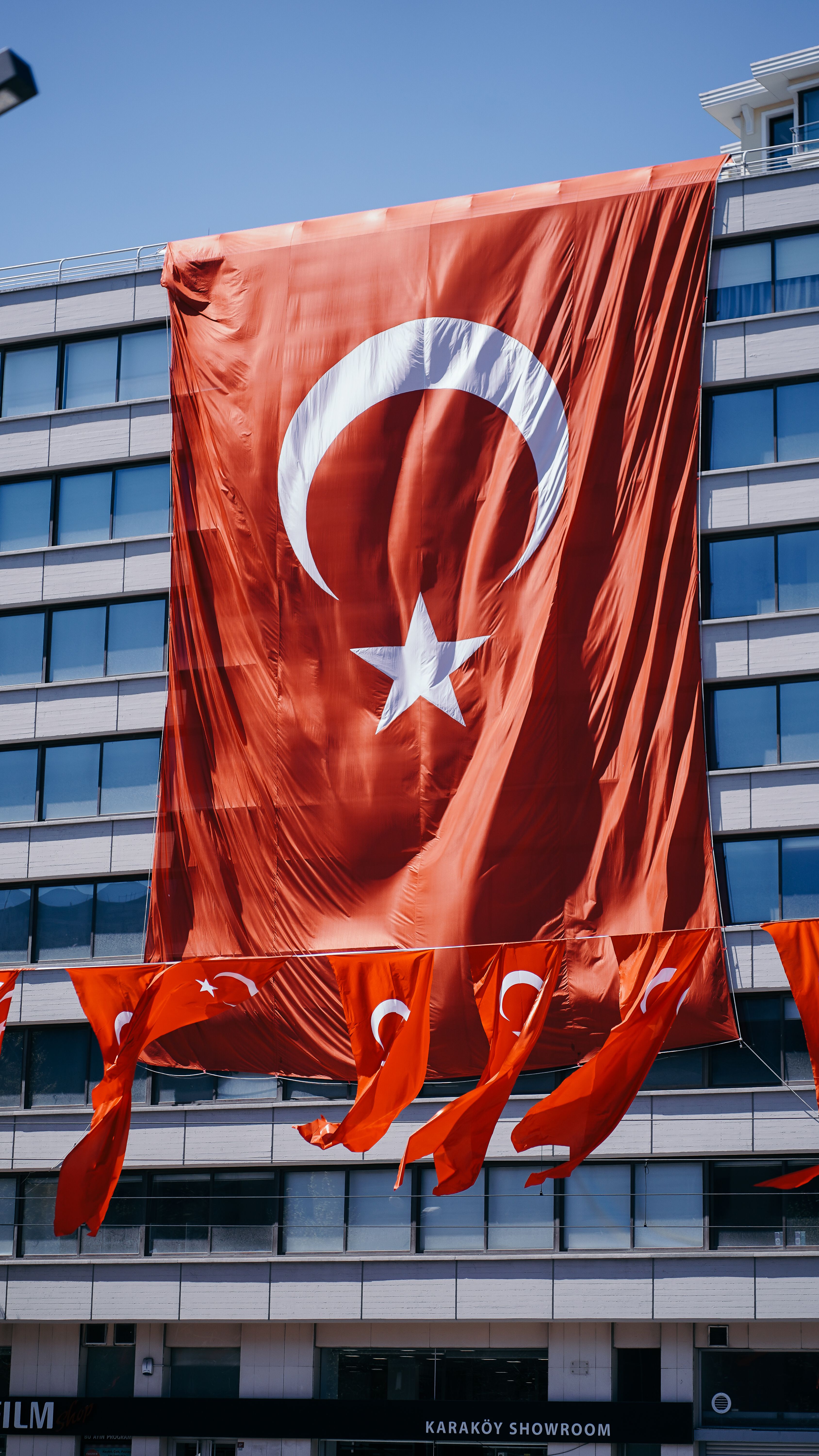 Large Turkish flag hanging prominently on a building in Istanbul during a sunny day.
