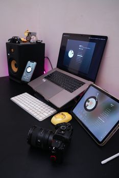 A stylish and modern office desk setup with various tech gadgets including a laptop, tablet, and camera.