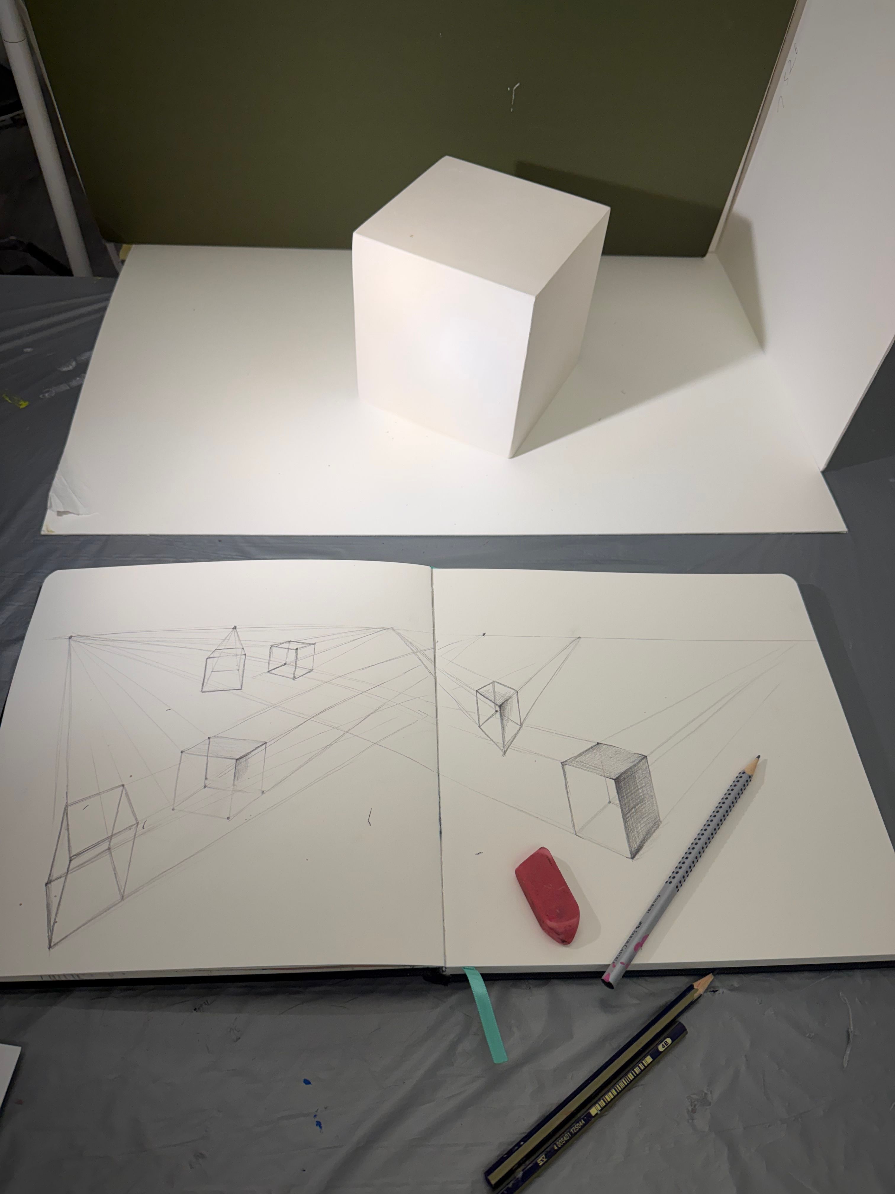 Sketchbook with geometric drawings and shading studies on a tabletop.