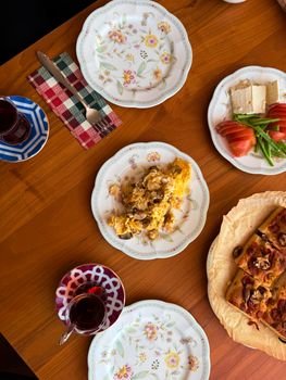 Inviting brunch with scrambled eggs, pastries, and tea on a wooden table.