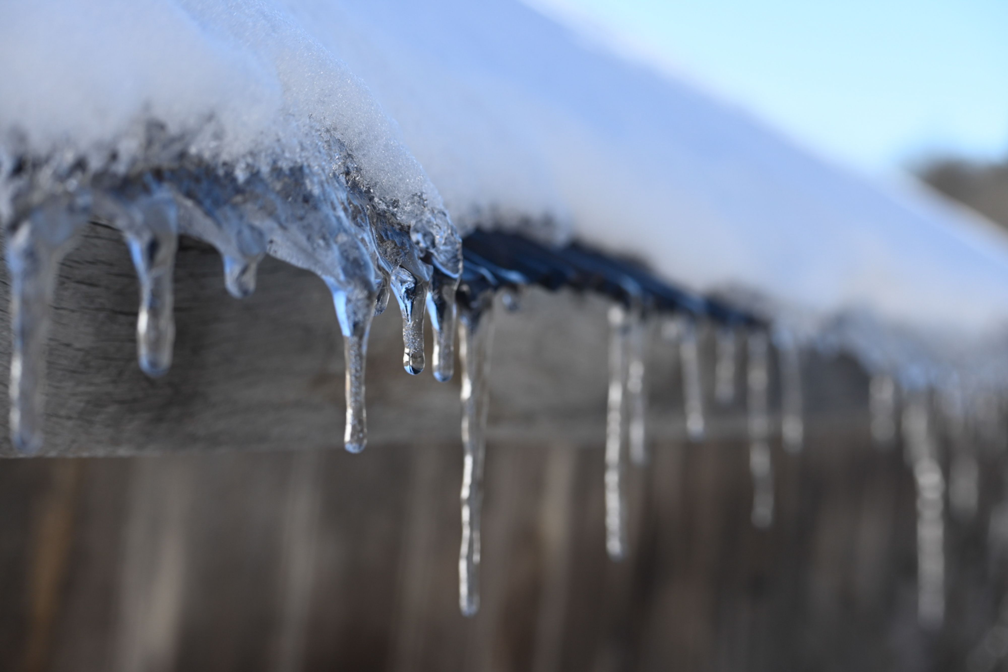 Icicles hanging from the edge of a timber roof in freezing weather