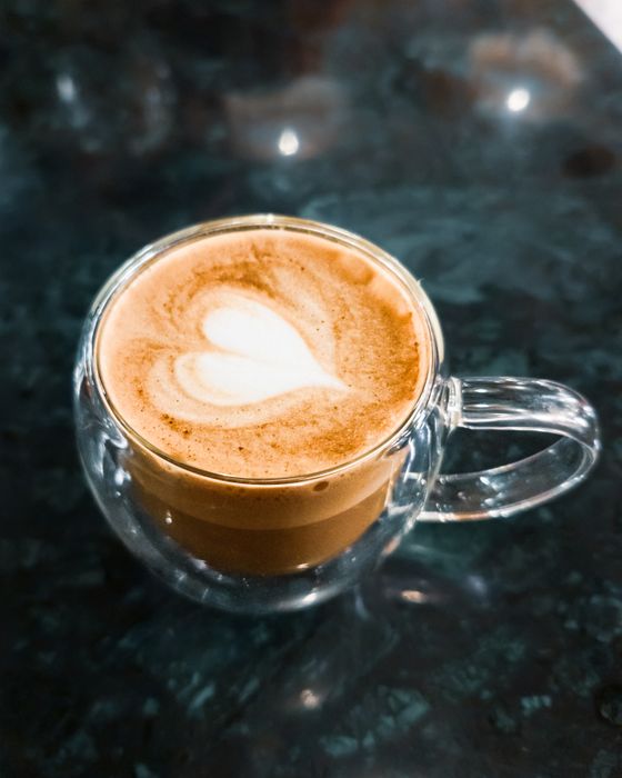 Cafe latte with a white heart of milk foam in a double-walled glass cup