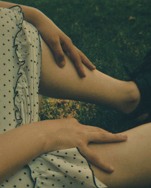 Free A person in a white polka dot dress relaxes on grass, capturing a peaceful summer moment. Stock Photo