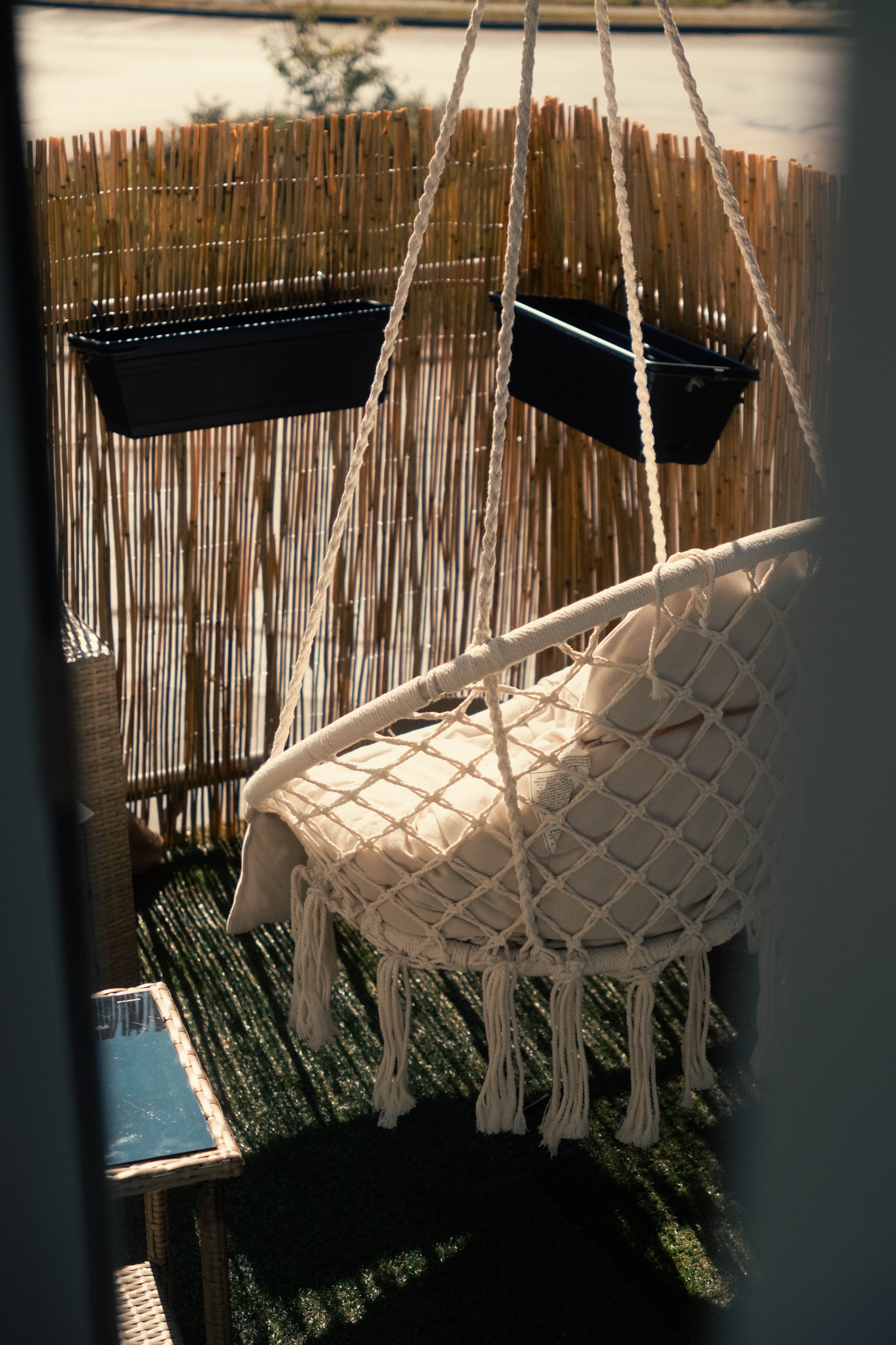Retractable beige privacy screen mounted on a small apartment balcony railing