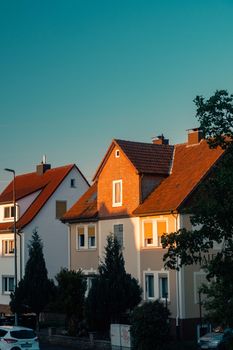 Sunset light on traditional German houses with red roofs in a serene neighborhood.