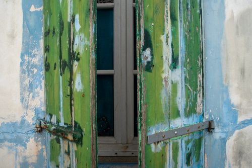 Free A close-up of rustic green and blue weathered wooden shutters on an old building exterior. Stock Photo