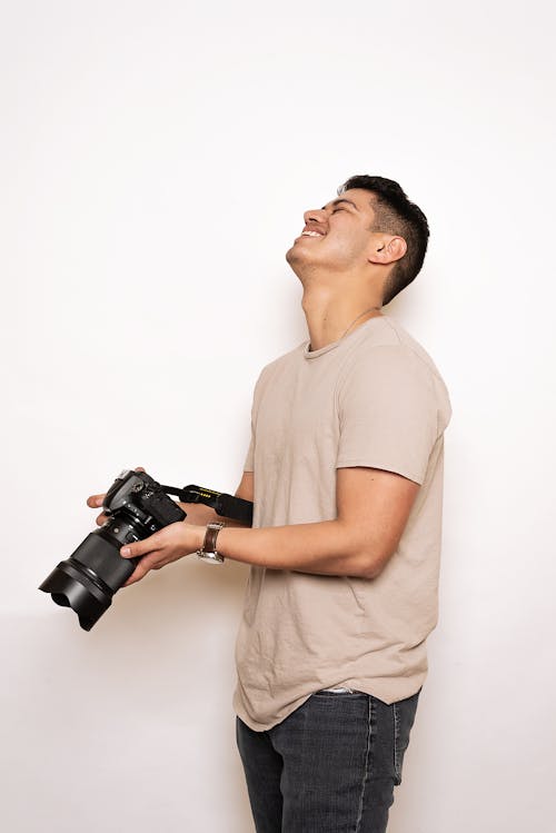 Free Man in Brown Crew Neck T-shirt Holding A Black Dslr Camera Stock Photo