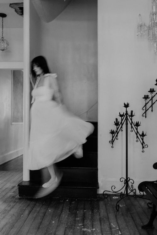 Free Black and white photo of a woman in motion gracefully descending a staircase. Stock Photo